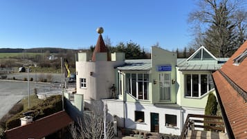 A building with a tower, a sign reading "Caststätte '5 Kontinente'", and a paved courtyard with potted plants.
