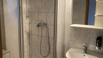 Ein modernes Badezimmer mit einer gläsernen Dusche, einem weißen Waschbecken und einem Spiegel darüber.