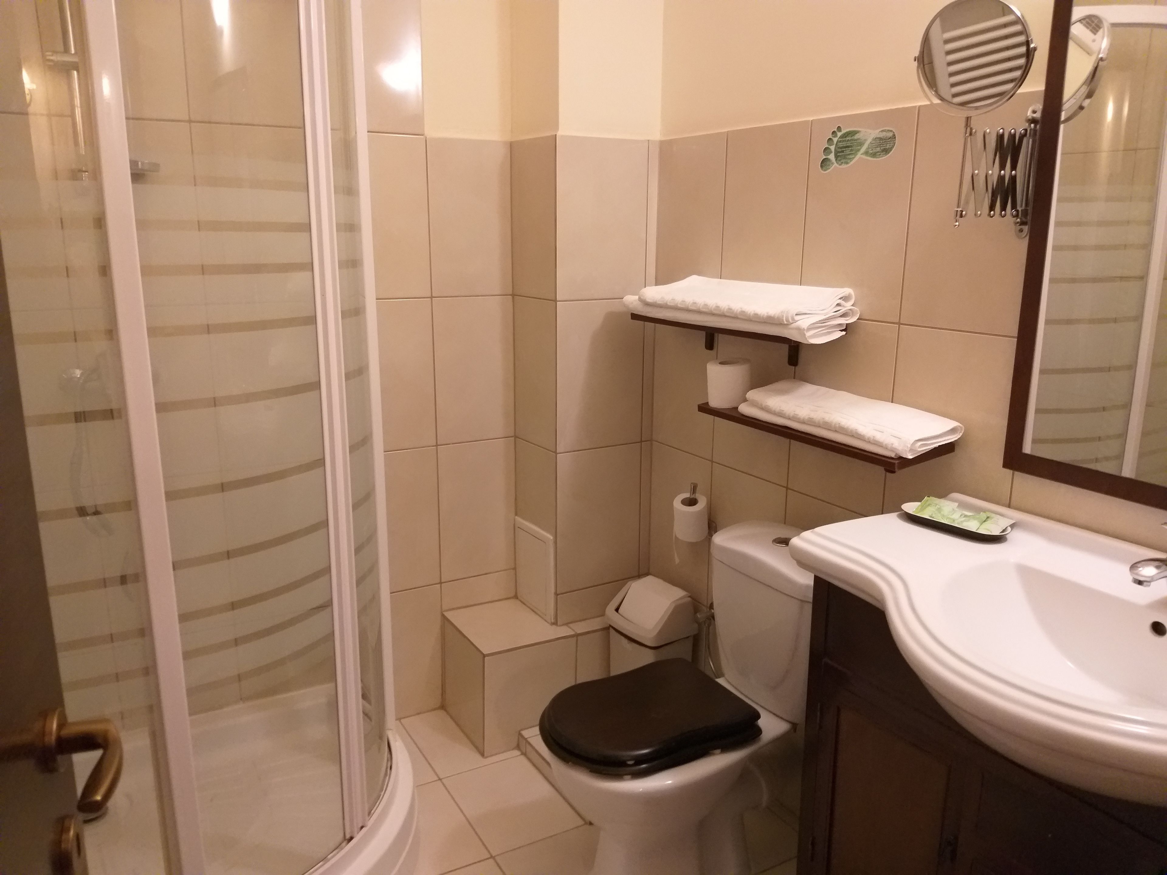 Un baño con inodoro, lavamanos, ducha y perchero para toallas.