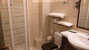 Un baño con inodoro, lavamanos, ducha y perchero para toallas.