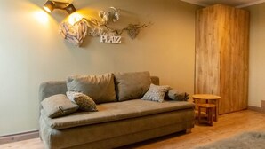 Un salon chaleureux avec un canapé, des coussins, une petite table en bois et un élément décoratif mural.