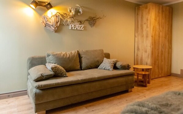 A cozy living room with a sofa, cushions, a small wooden table, and a decorative wall piece. - Gasthof Obere Mühle (Blankenburg)