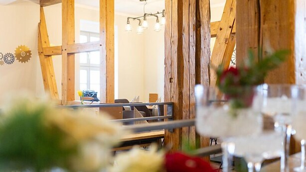 Un espace repas agrémenté de poutres en bois, d’un lustre et d’une table mise pour le repas.