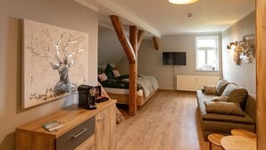 Un salon chaleureux avec un plancher en bois, un canapé, une table basse et un tableau accroché au mur.