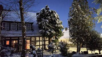 A snow-covered landscape with a house and trees.