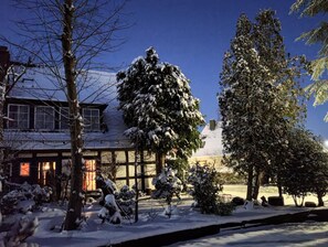 A snow-covered landscape with a house and trees.
