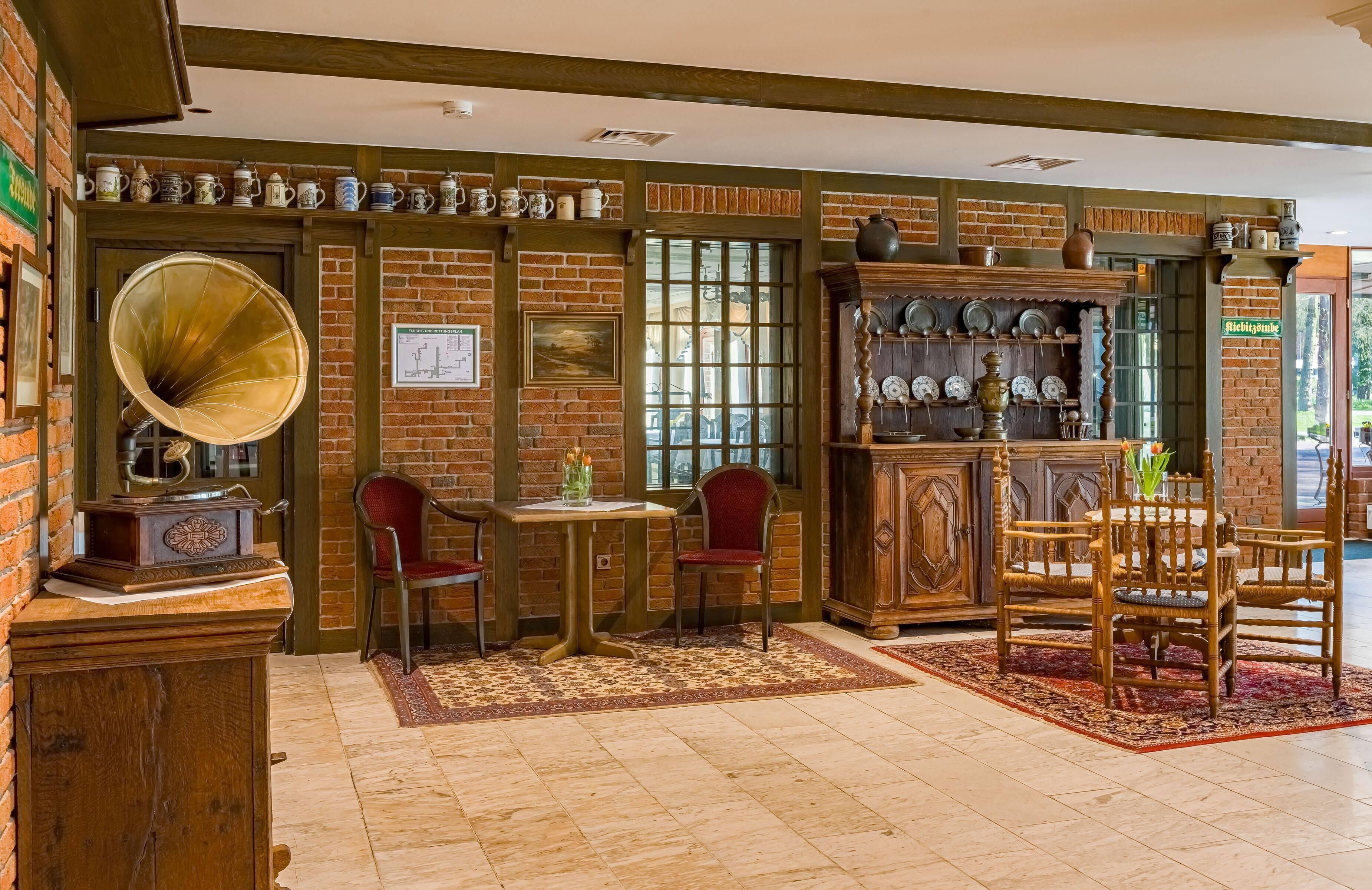 A cozy room with a brick wall, a wooden cabinet with dishes, a table with chairs, and a vintage gramophone.