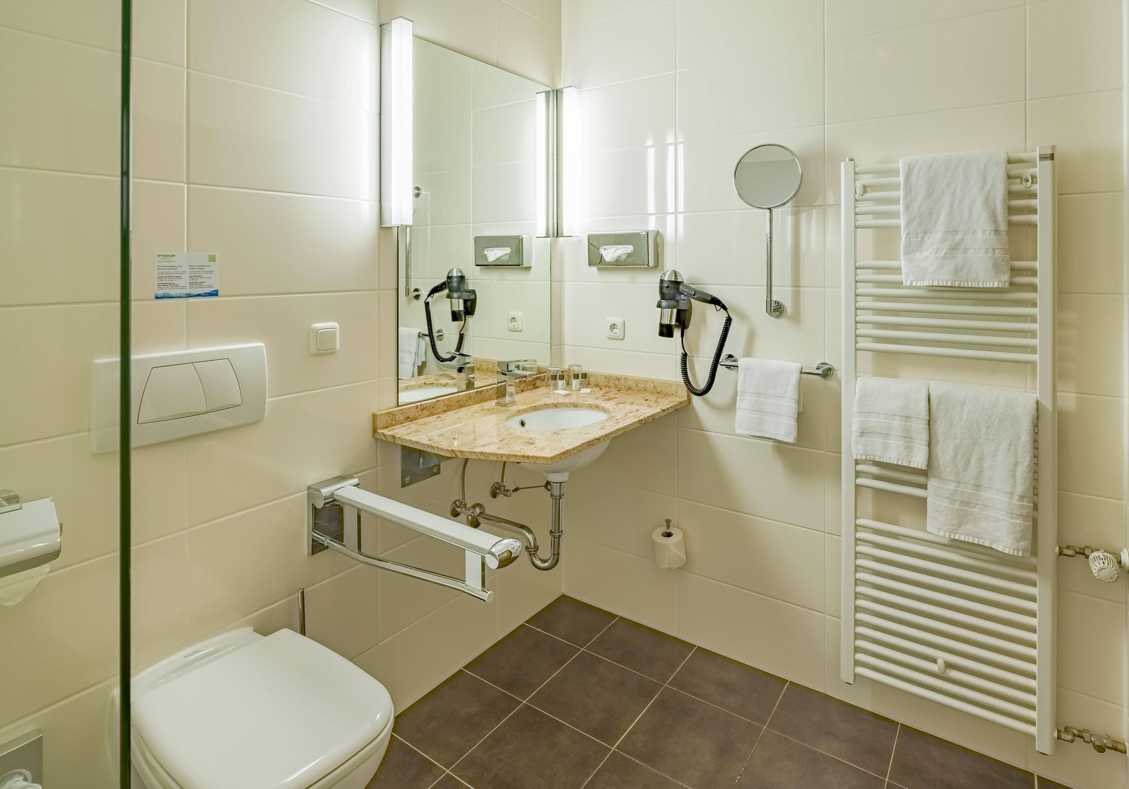 A bathroom with a sink, mirror, towel rack, and toilet.