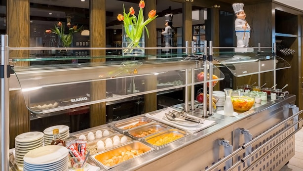 A buffet setup with various food items and utensils. - Aspire Oldenburg, Trademark Collection by Wyndham (Oldenburg)