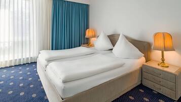Una habitación de hotel con una cama grande, dos mesitas de noche y una mesita auxiliar con lámparas.