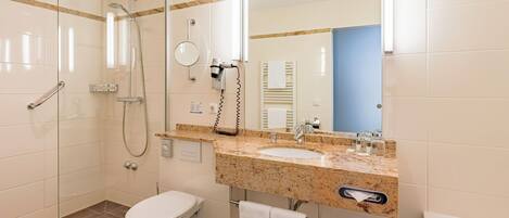 Un baño moderno con ducha envuelta en vidrio, inodoro e lavabo con encimera de mármol.