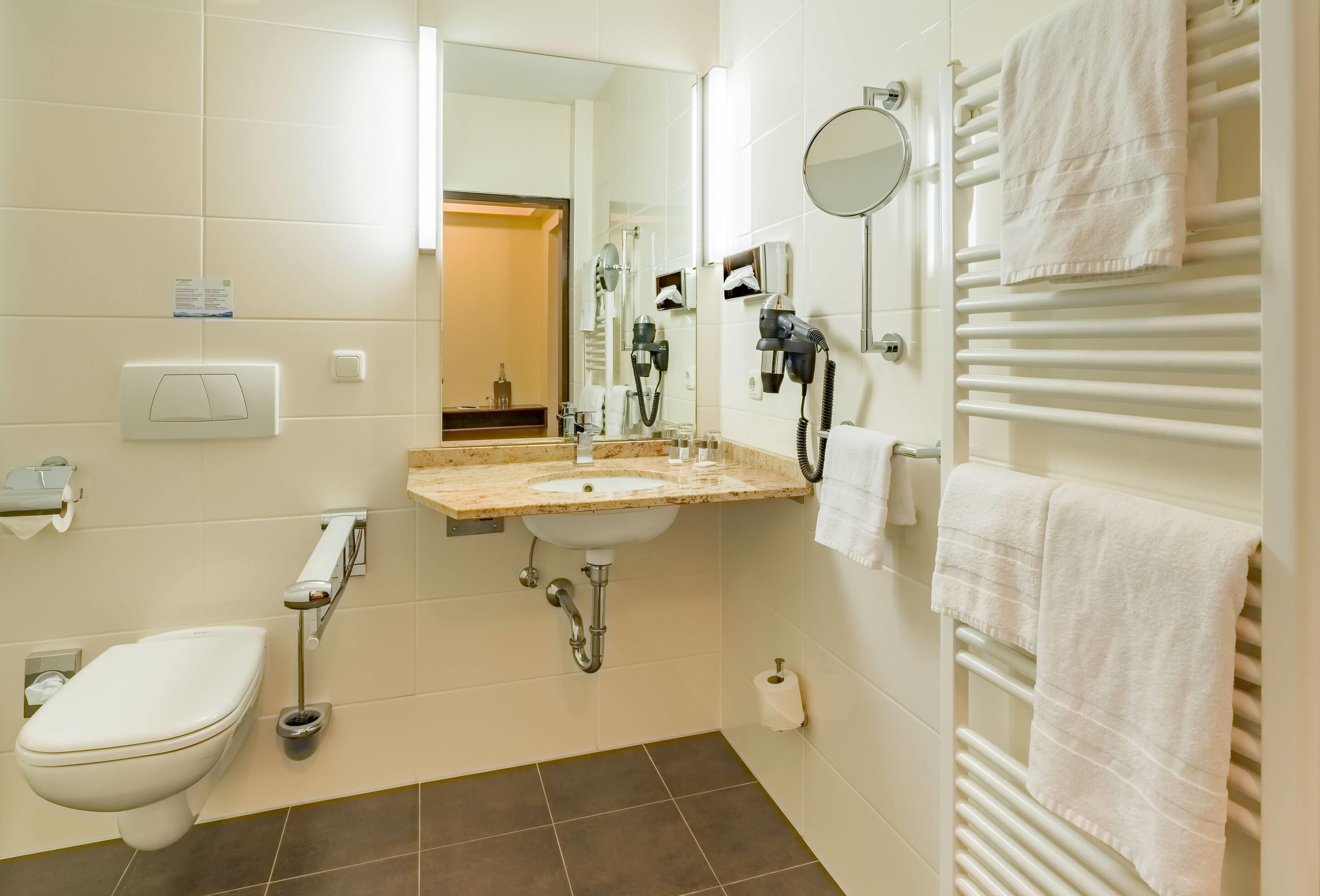 Un baño moderno con inodoro, lavabo, toallero y secador de pelo.