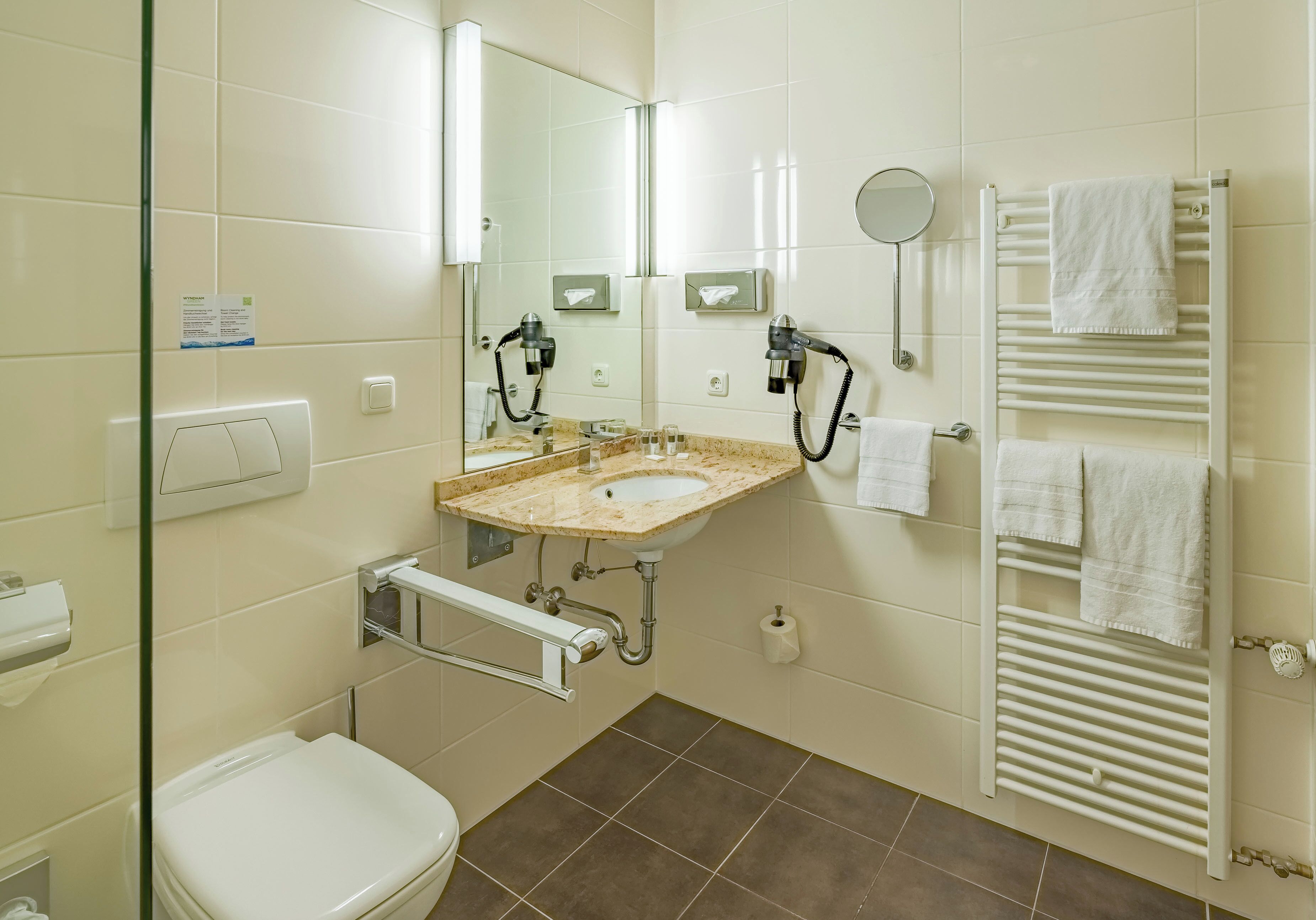 Un baño con lavamanos, espejo, toallero y retrete.