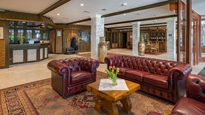 A lobby with leather sofas, a wooden coffee table, and a patterned carpet. - Aspire Oldenburg, Trademark Collection by Wyndham (Oldenburg)