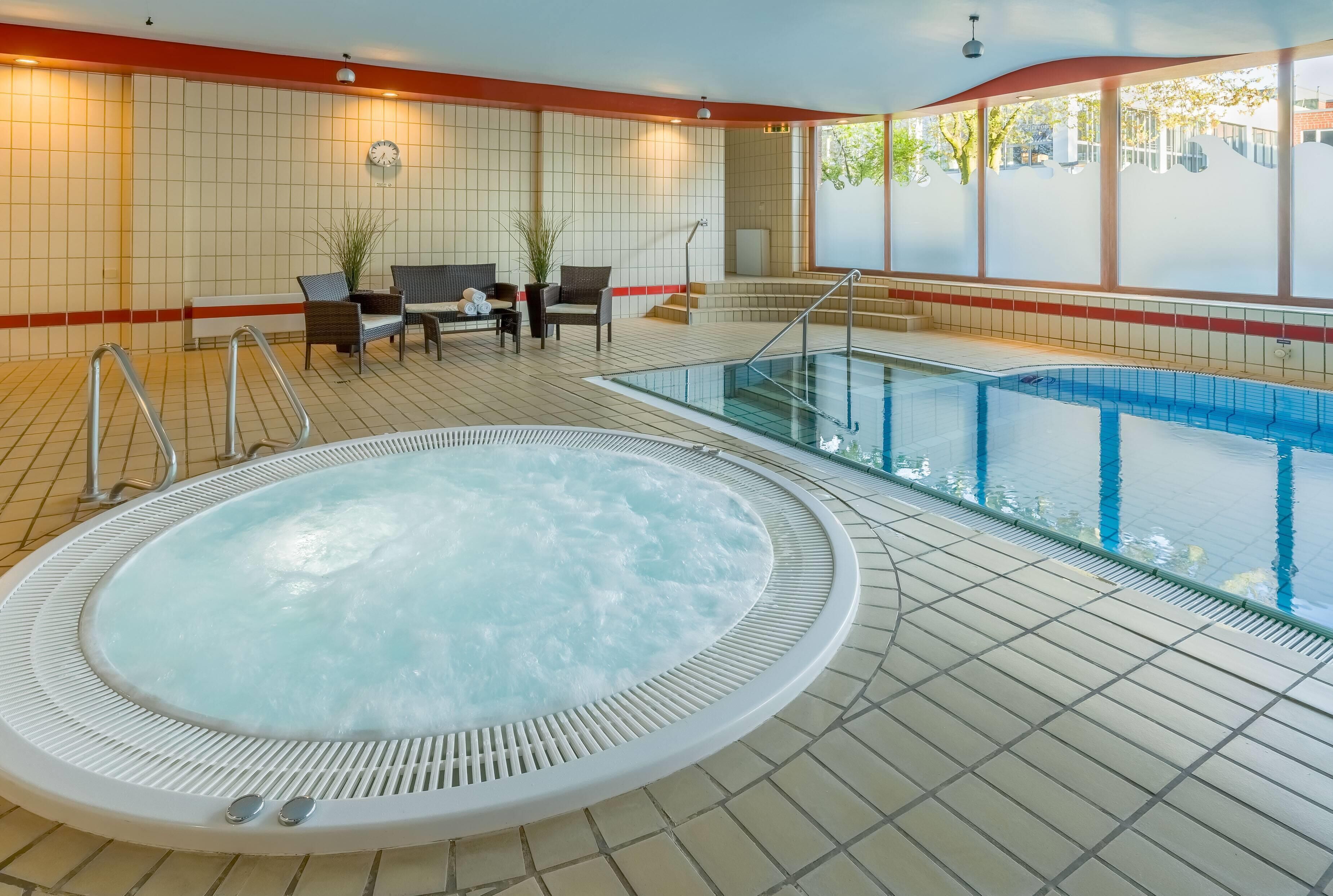 Een wellnessruimte met een jacuzzi, zitplaatsen en een zwembad.
