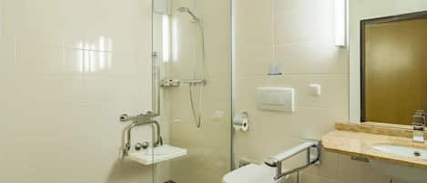 A modern bathroom with a glass shower enclosure, a white toilet, a sink with a mirror, and a tiled floor.