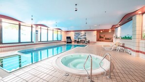 An indoor swimming pool with a hot tub, sun loungers, and a view of the outdoors through large windows. - Aspire Oldenburg, Trademark Collection by Wyndham (Oldenburg)