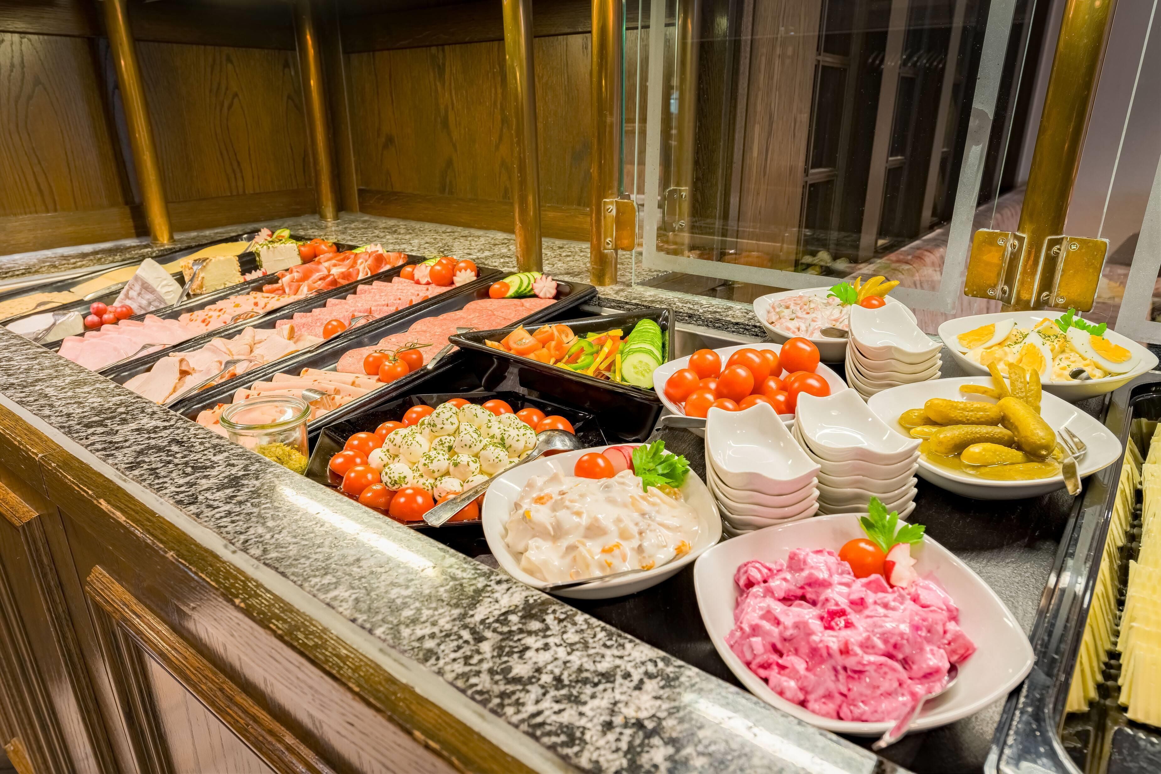 A buffet with various food items including meats, salads, and dips.