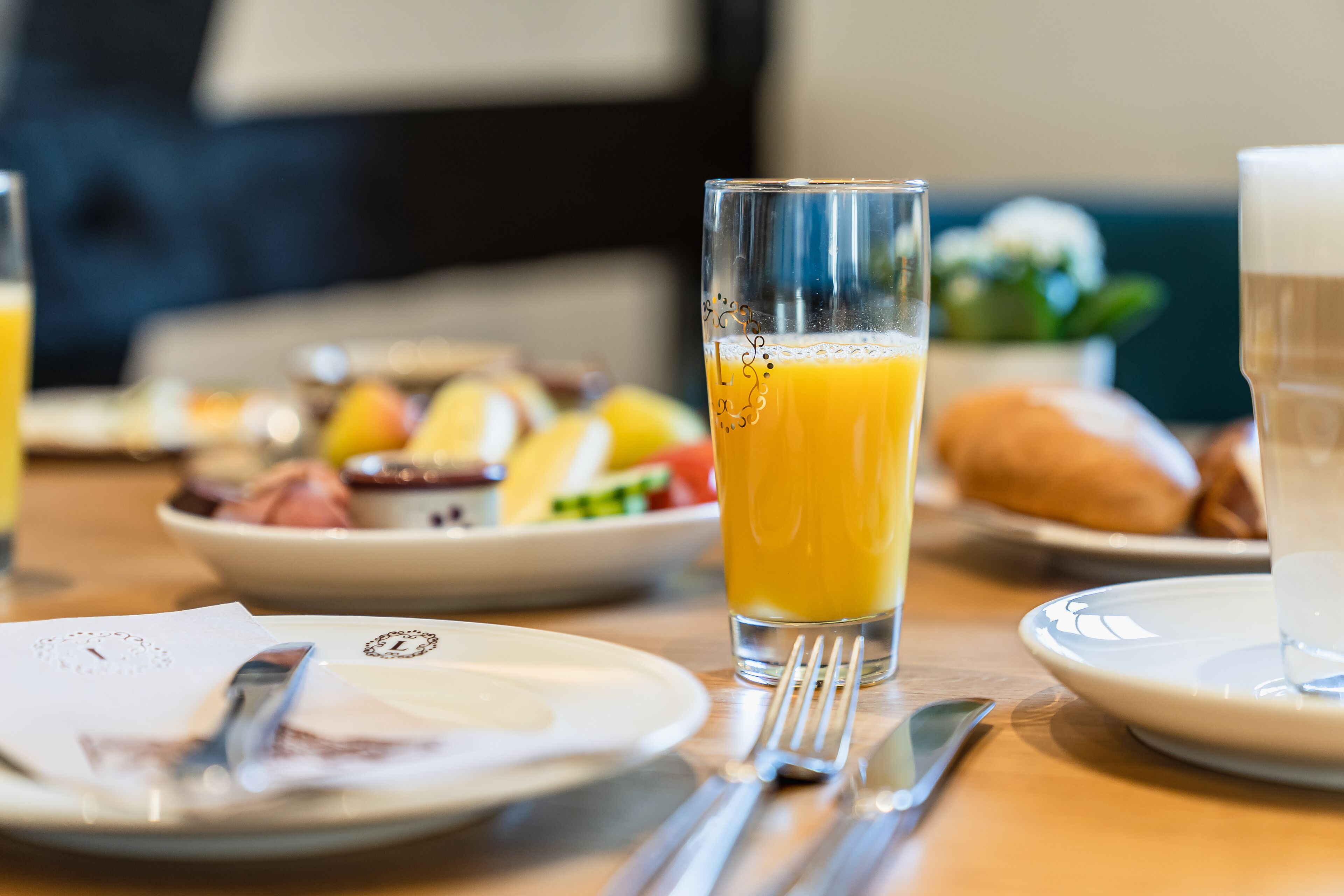 A breakfast setting with a glass of orange juice, a plate of food, and a cup of coffee on a wooden table.