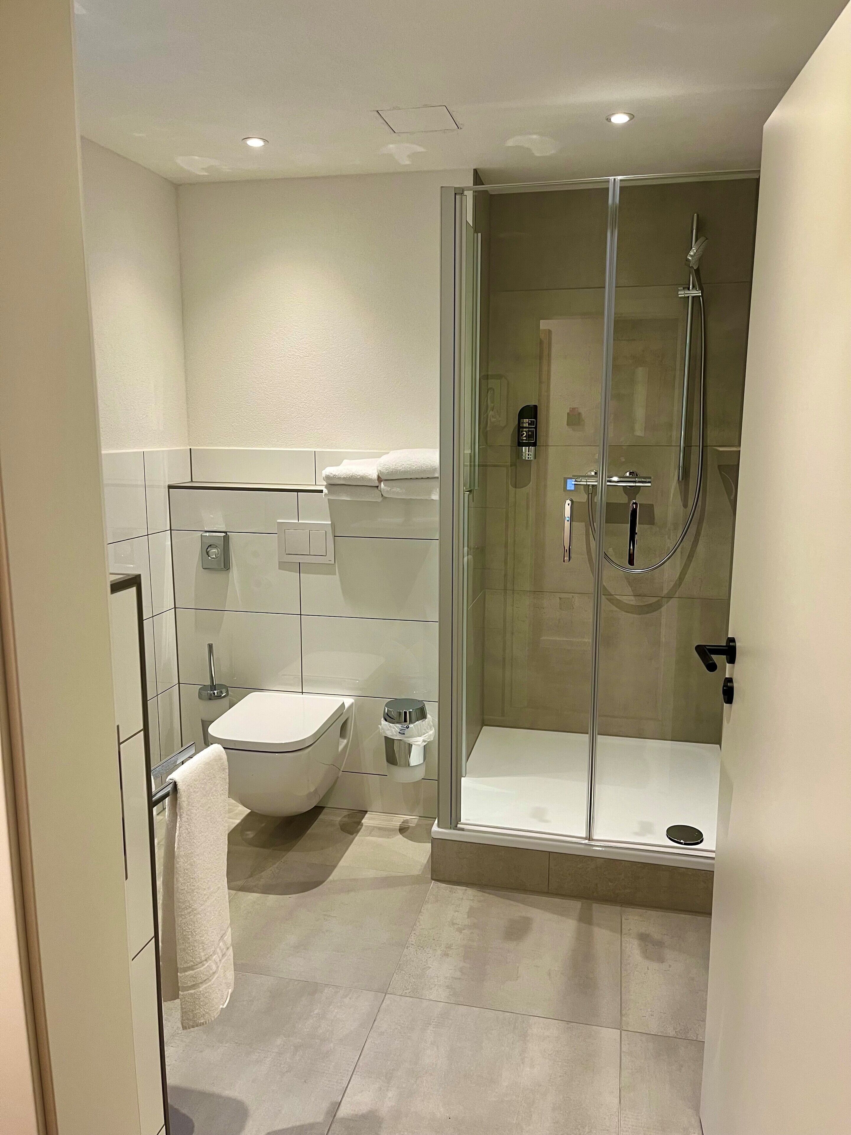 A modern bathroom with a glass-enclosed shower, a toilet, and a bidet.