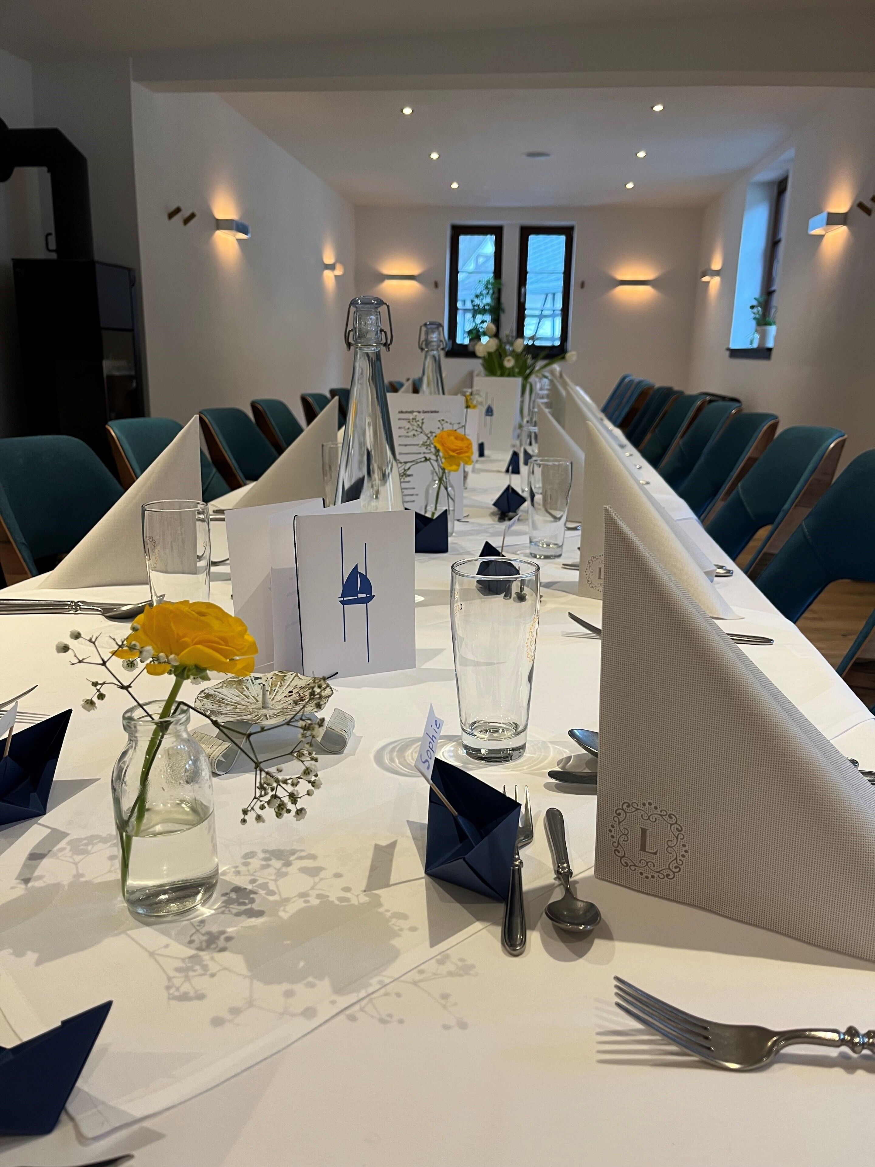 Ein Konferenzraum mit einem langen Tisch, Stühlen und verschiedenen Gegenständen, darunter eine Vase mit einer Blume, ein Glas und Namensschilder.