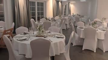 Une salle de banquet avec des tables rondes, des nappes blanches et des chaises.