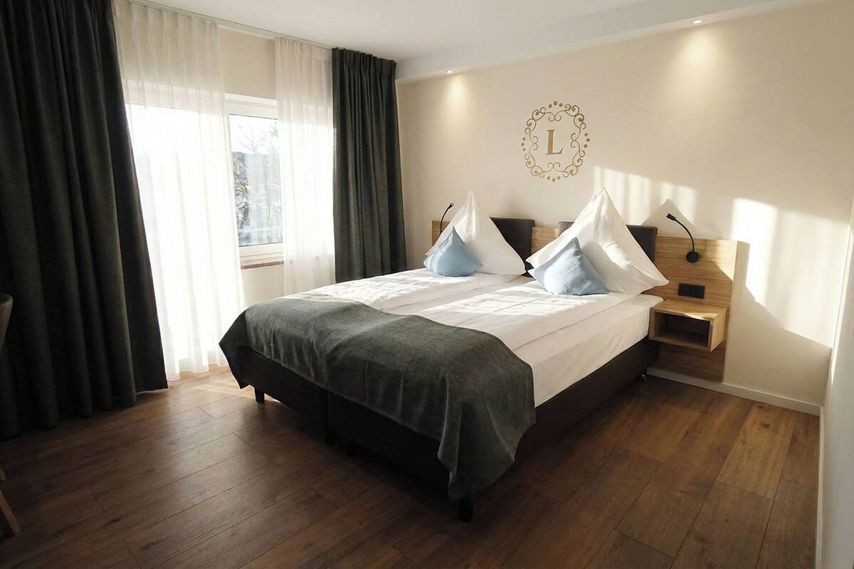 Une chambre à coucher bien rangée, avec un grand lit, une table de chevet, une commode et un luminaire fixé au mur.