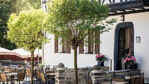 A traditional half-timbered building with outdoor seating and a stone staircase leading to the entrance. - Landgasthof zur Burg Grenzau (Hoehr-Grenzhausen)