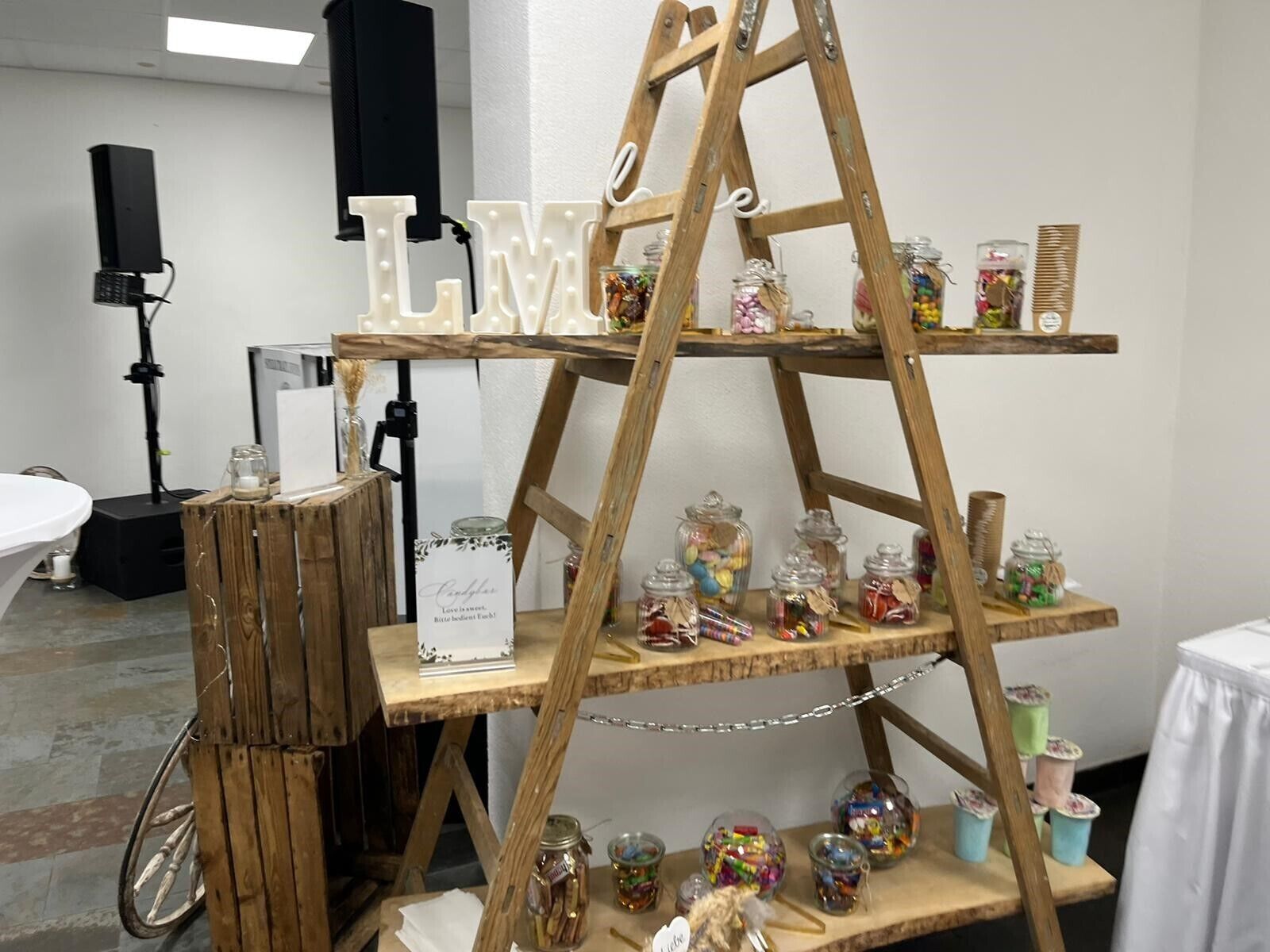 Una escalera de madera exhibe botes de caramelos y un letrero que dice 'Love is sweet'.