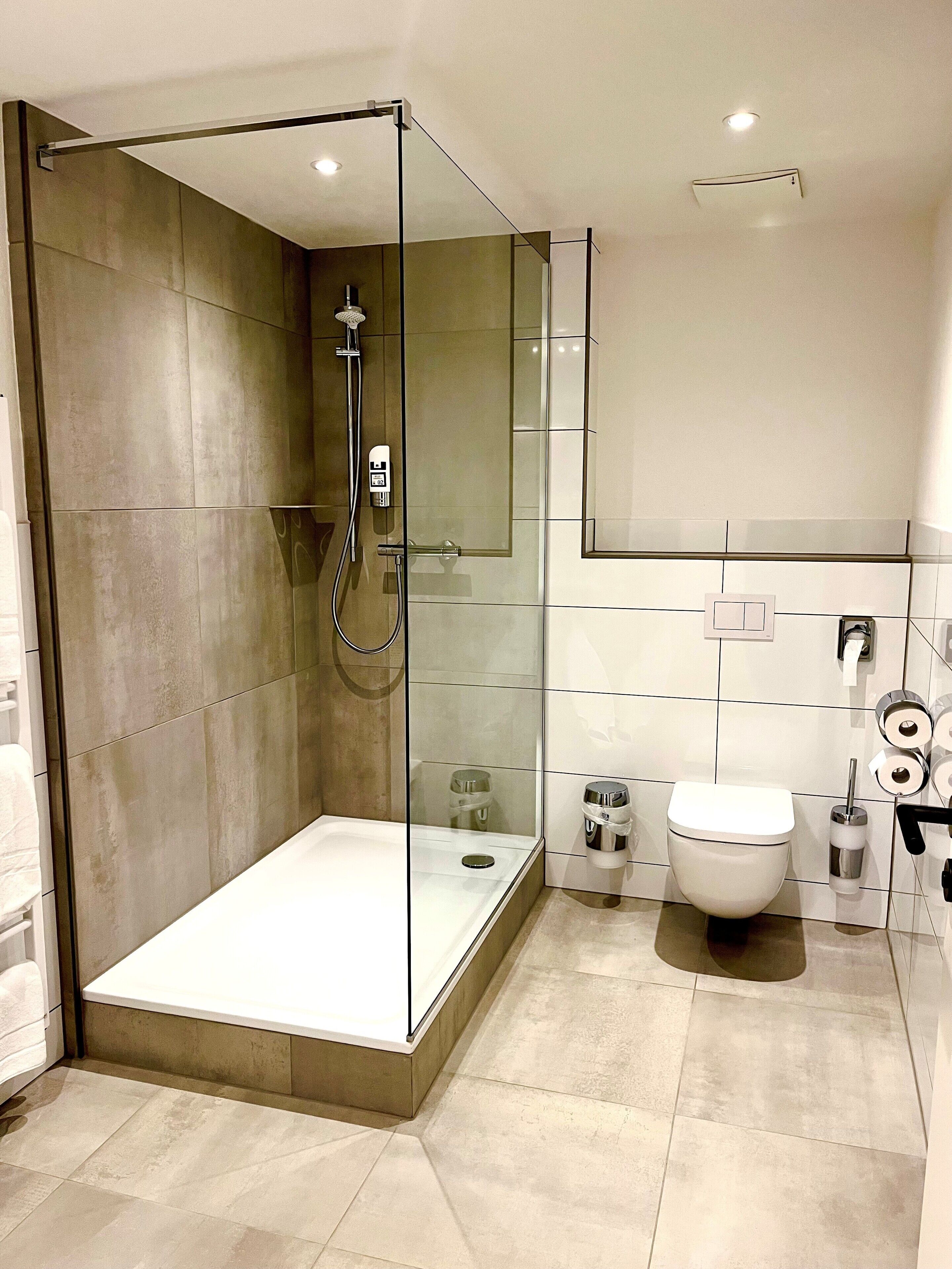 A modern bathroom with a glass-enclosed shower, a toilet, and a bidet.