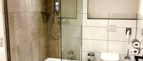 A modern bathroom with a glass-enclosed shower, a toilet, and a bidet.