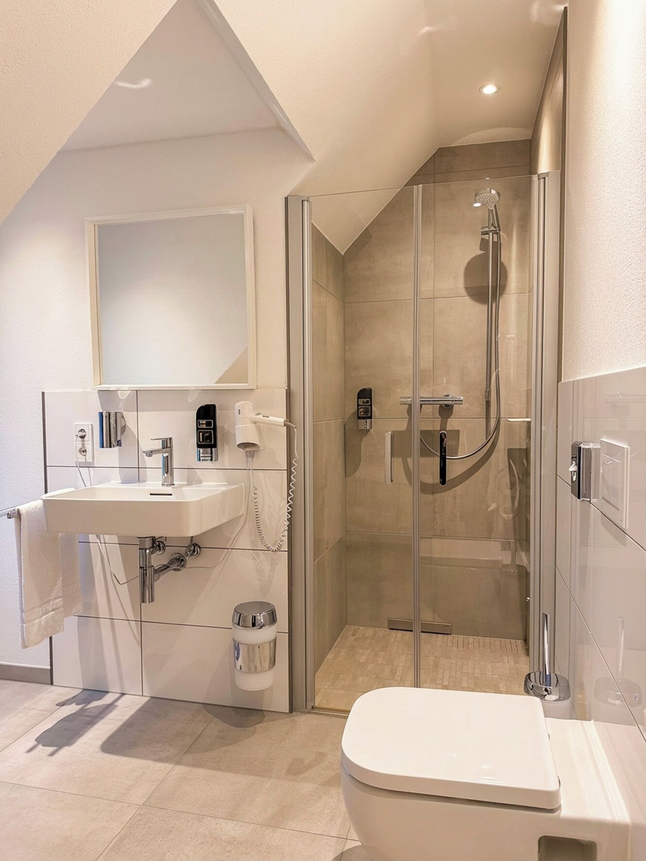 A modern bathroom with a glass-enclosed shower, a white sink, and a toilet.