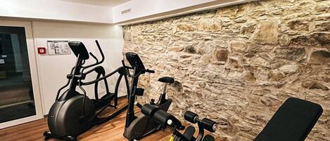 A gym with exercise equipment including an elliptical, a stationary bike, and a bench.