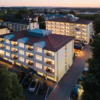 A multi-story hotel with a parking lot in front.