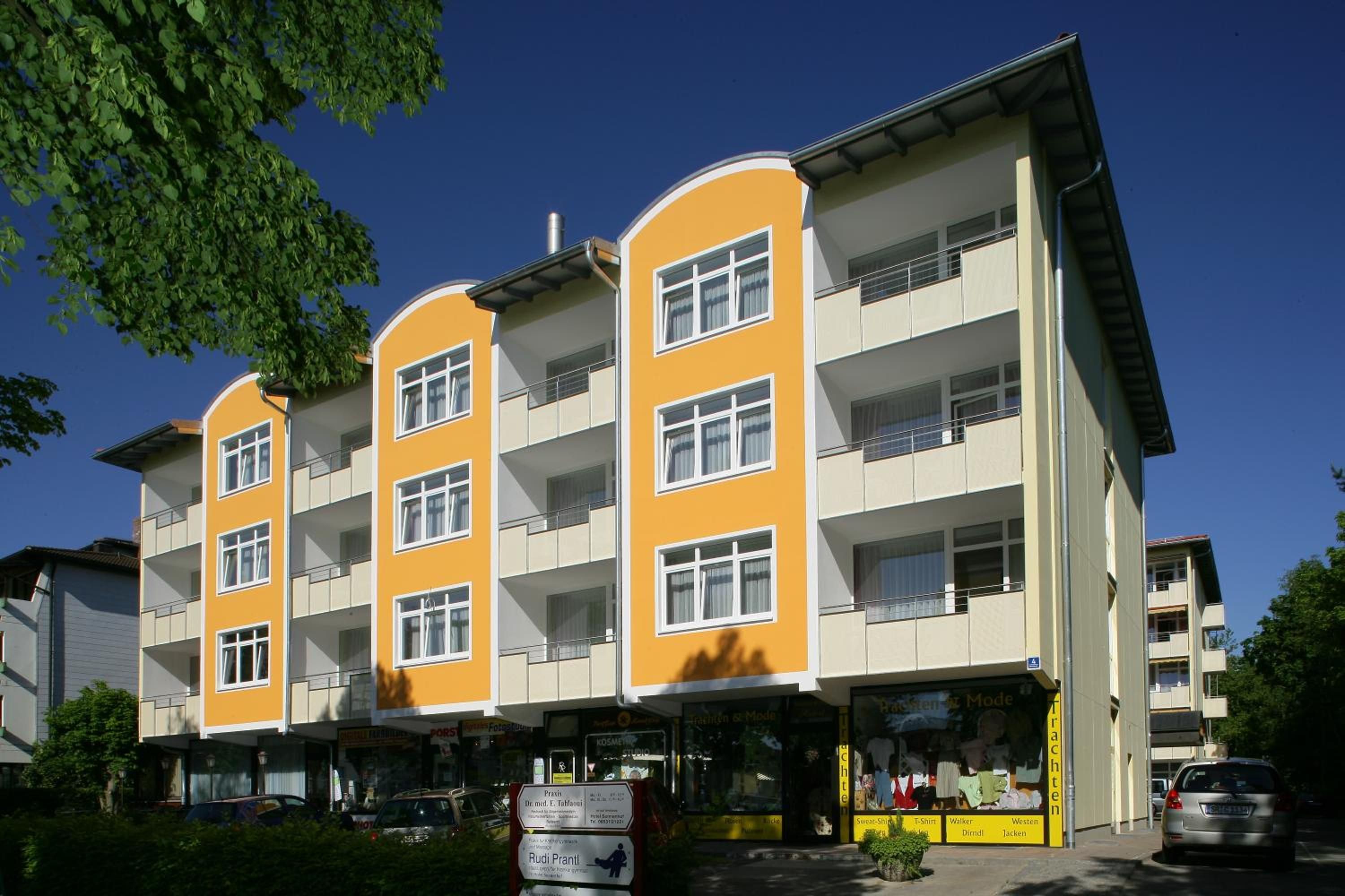 Ein mehrstöckiges Gebäude mit Balkonen und einem Laden im Erdgeschoss.