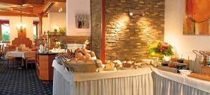 A buffet setup with a variety of food items, a stone wall, and a dining area with tables and chairs. - Kurhotel Sonnenhof (Bad Fuessing)