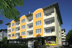 Un edificio de varios pisos con balcones, una tienda en la planta baja y un estacionamiento.