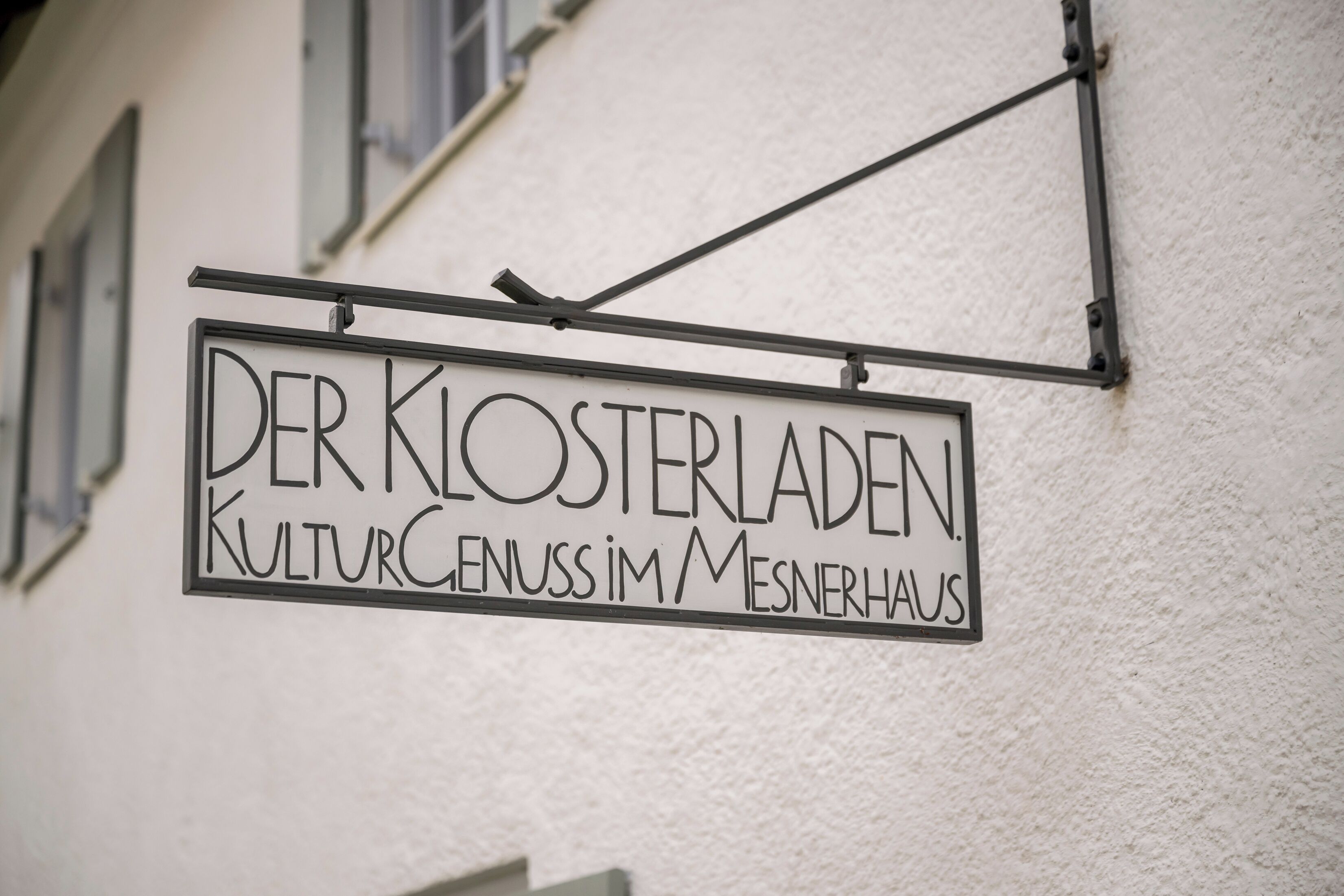 Schild für "Der Klosterladen Kulturgenuss im Mesnerhaus", an einem Gebäude befestigt.