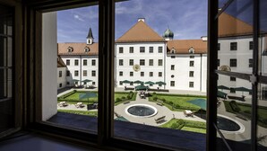 A courtyard with a fountain, outdoor seating, and umbrellas. - Kloster Seeon (Seeon-Seebruck)