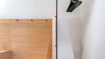 A minimalist bedroom with a wooden bed, a black bedside table, and a wall-mounted light fixture.