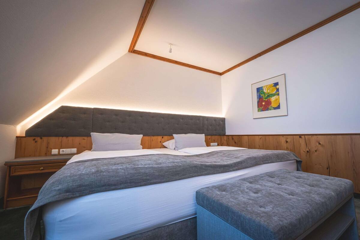 A bedroom with a large bed, wooden headboard, and a bench.