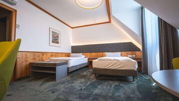 Habitación de hotel con dos camas, una mesa de comedor, una silla, una lámpara en el techo y un cuadro en la pared.