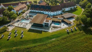 Une vue aérienne d’un vaste domaine comprenant plusieurs bâtiments, une piscine et de vastes champs verdoyants.
