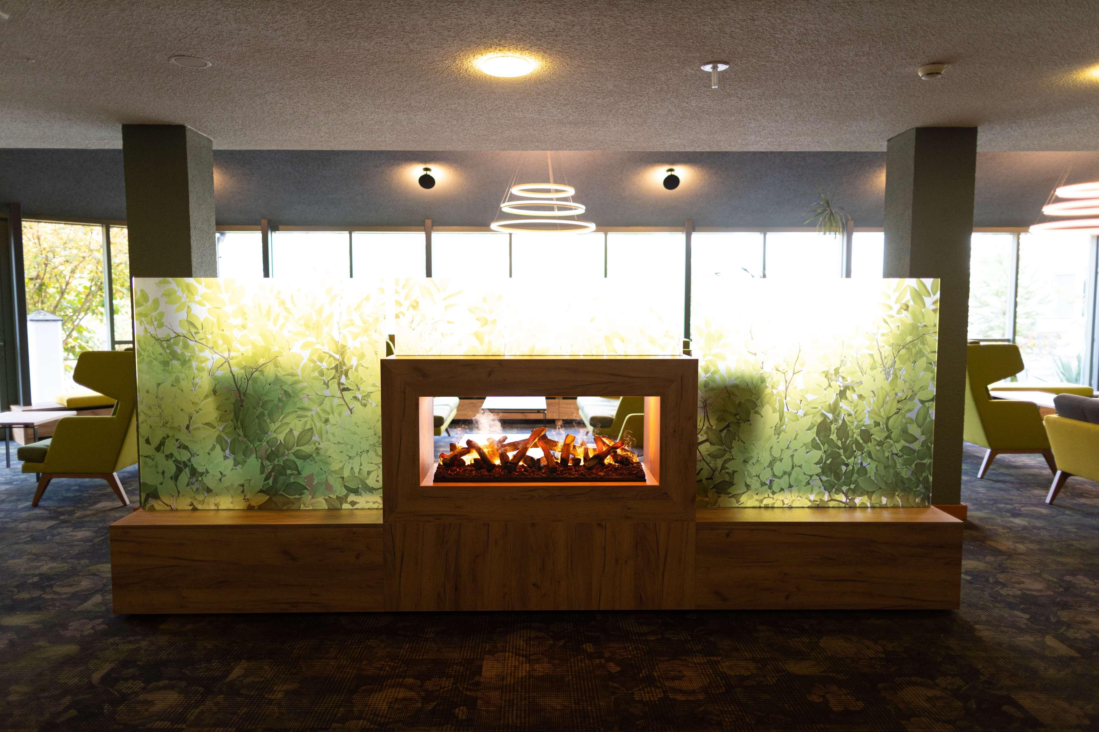 A reception area with a wooden fireplace, large windows, and modern chairs.