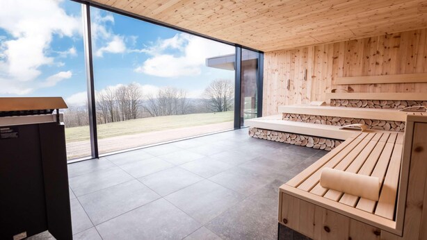 Une salle de spa moderne avec des murs en bois, une grande fenêtre en verre et un banc en bois.
