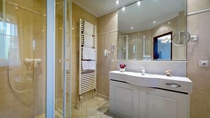 A modern bathroom with a glass shower enclosure, a white vanity with a mirror, and a towel rack. - Hotel Sacher Stoiber (Bad Fuessing)