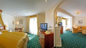 A hotel room with a bed, a desk, a television, and a seating area. - Hotel Sacher Stoiber (Bad Fuessing)