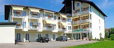 A multi-story hotel with balconies, a sign reading 'Südler-Stöder,' and cars parked in front.