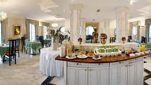 A luxurious dining area with marble columns, green tablecloths, and a variety of breakfast items. - Hotel Sacher Stoiber (Bad Fuessing)