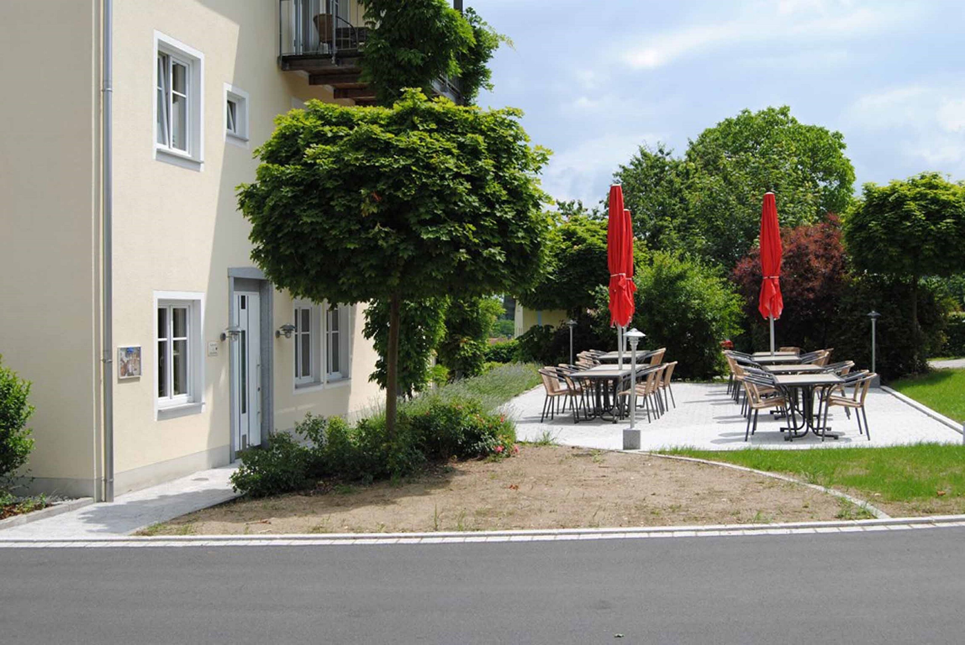A building with outdoor seating and a tree in front.